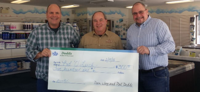 3 men smiling and holding check