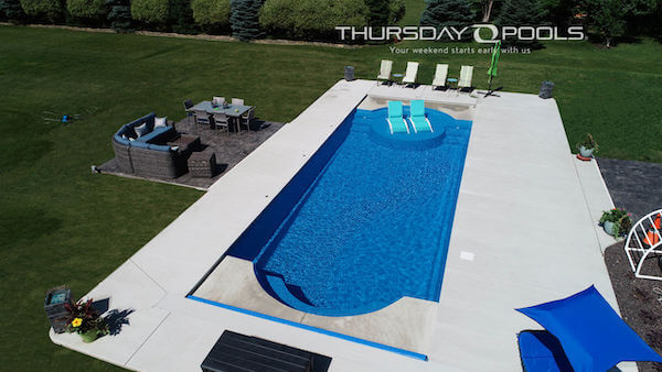 Installed Cathedral LX fiberglass pool with rounded ends and concrete deck
