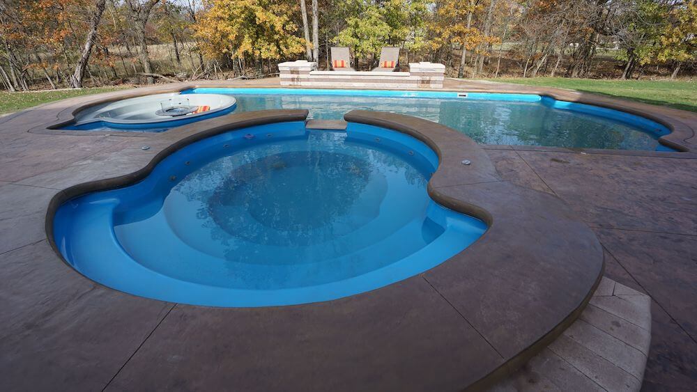 Installed Grand Spa with spillover beside a freeform fiberglass pool