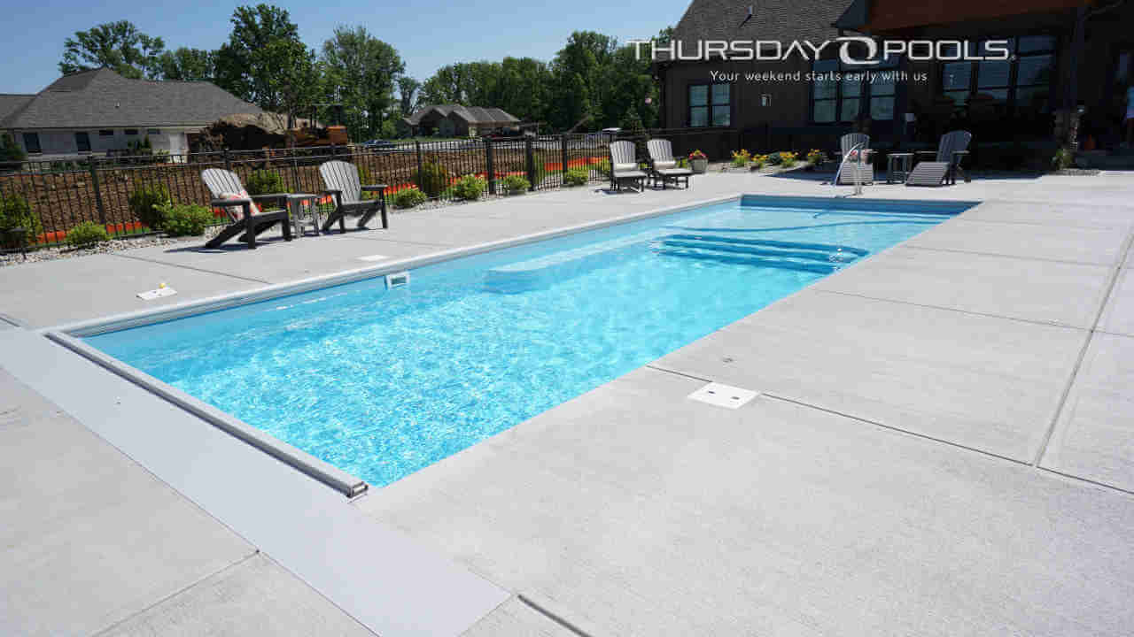 Installed Lil Bob LX fiberglass pool with flat bottom and broom-finished concrete deck