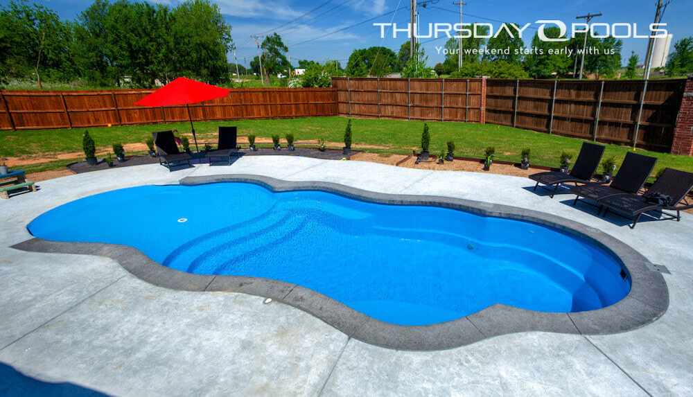 Installed Sandal Beach Entry fiberglass pool with shallow beach area and stamped concrete deck