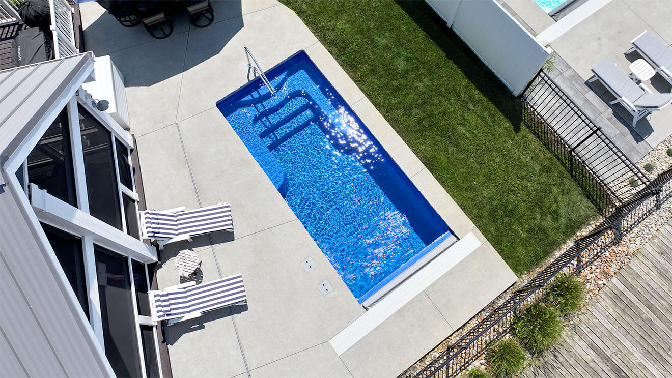 Installed Sea Turtle fiberglass pool in a compact backyard with concrete deck