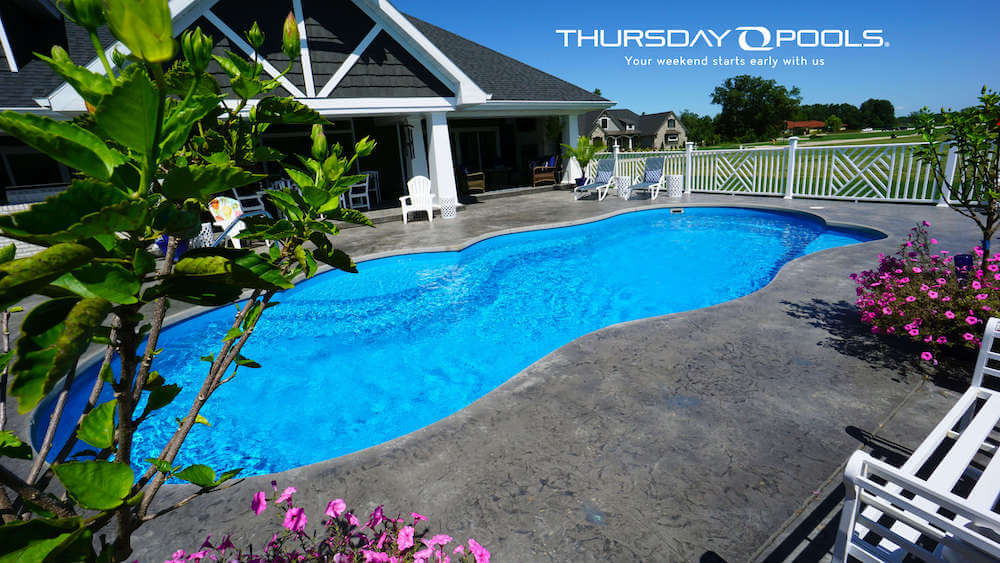 Installed Sun Day freeform fiberglass pool with stamped concrete deck