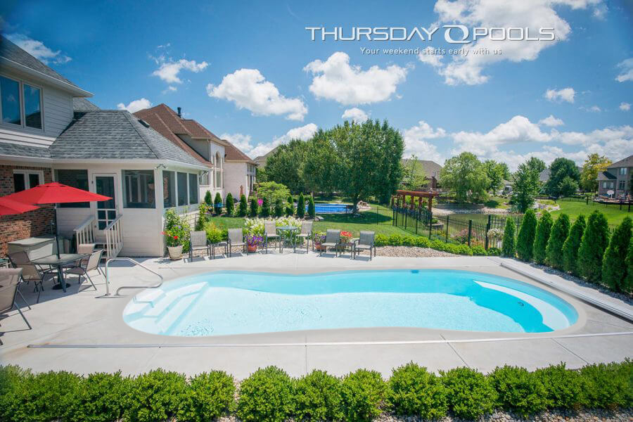 Installed Titus fiberglass pool with curved sides and concrete deck