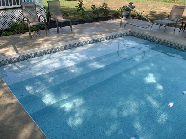 Vinyl liner inground pool with automatic safety cover and stamped concrete deck