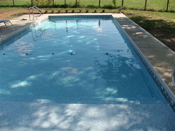 Vinyl liner inground pool with automatic safety cover and stamped concrete deck