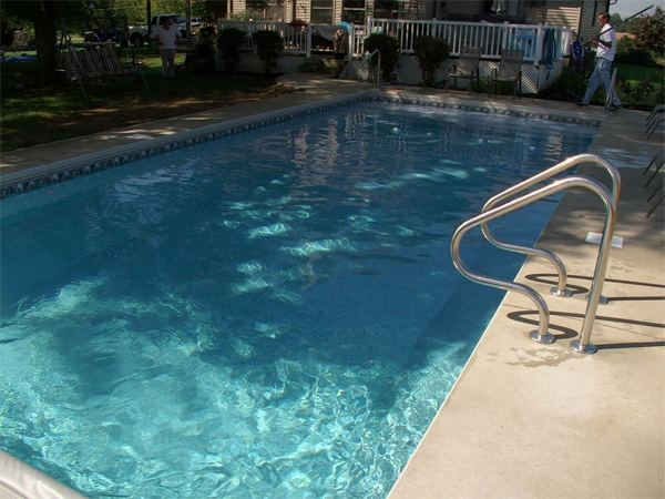 Vinyl liner inground pool with automatic safety cover and stamped concrete deck
