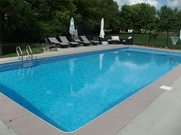 Vinyl liner inground pool with volleyball net and stamped concrete deck