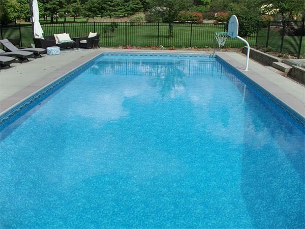 Vinyl liner inground pool with volleyball net and stamped concrete deck