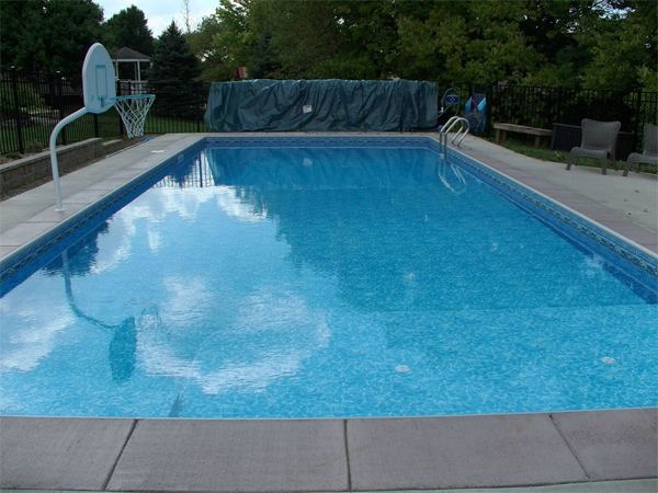 Vinyl liner inground pool with volleyball net and stamped concrete deck