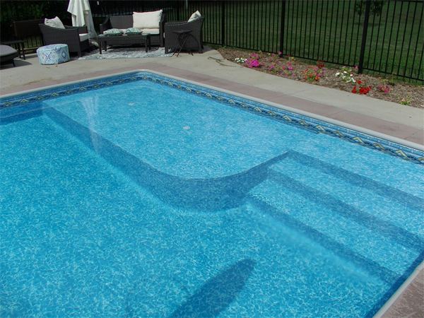 Vinyl liner inground pool with volleyball net and stamped concrete deck