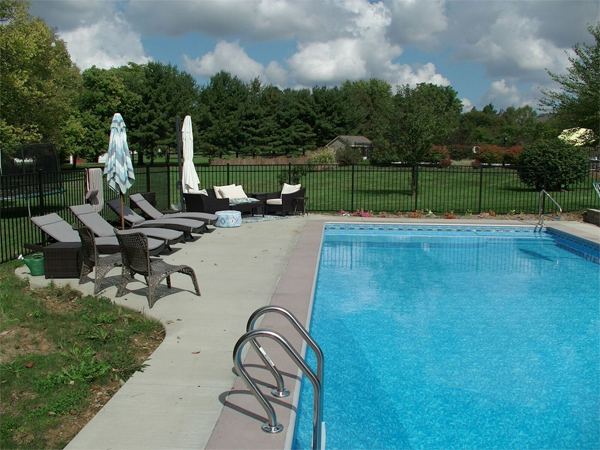 Vinyl liner inground pool with volleyball net and stamped concrete deck