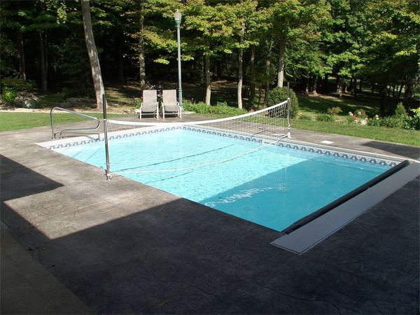 Fenced vinyl liner inground pool with patio seating area