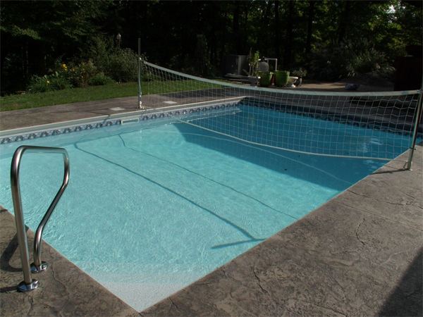 Fenced vinyl liner inground pool with patio seating area