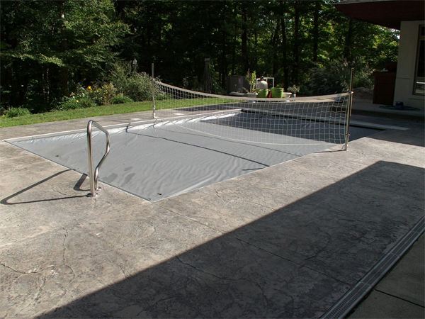 Fenced vinyl liner inground pool with patio seating area